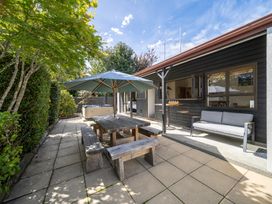 An outdoor patio with a table and umbrella at Te anau holiday home Te Anau