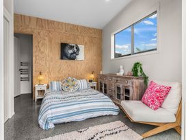 A bedroom with a bed and nightstands at Sweet Seabreeze - Mangawhai Heads Holiday Home, Mangawhai