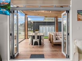An outdoor seating area with dining table and sofa at Sweet Seabreeze - Mangawhai Heads Holiday Home