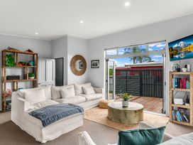 A living room with a sofa, coffee table, and bookshelf at Sweet Seabreeze - Mangawhai Heads Holiday Home, Mangawhai