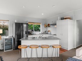 A kitchen with refrigerator and stools at Sweet Seabreeze - Mangawhai Heads Holiday Home, Mangawhai
