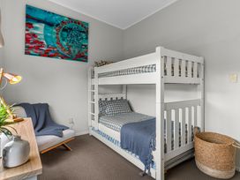 A bedroom with bunk beds and artwork at Sweet Seabreeze - Mangawhai Heads Holiday Home