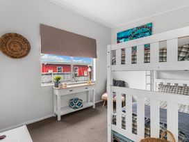 A bedroom with a bunk bed and a table at Sweet Seabreeze - Mangawhai Heads Holiday Home, Mangawhai