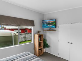 A bedroom with a television and bookshelf at Sweet Seabreeze - Mangawhai Heads Holiday Home, Mangawhai