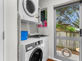 A laundry room with washer sink and dryer at Sweet Seabreeze - Mangawhai Heads Holiday Home Mangawhai