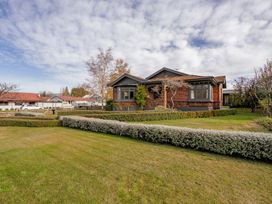 A house with lawn and trees at Cromwell Holiday Home in Cromwell