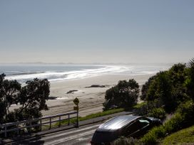 A beach view with a car parked on a road at Ahipara, Kaitaia