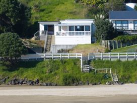 A house with a fence and stairs surrounded by grass at Ahipara in Kaitaia