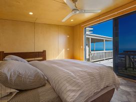 A bedroom with a bed and window at Ahipara in Kaitaia