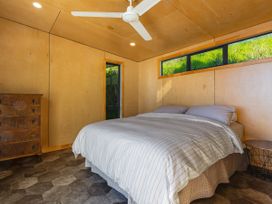 A bedroom with a bed and dresser at Ahipara in Kaitaia