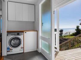 A laundry room with a washing machine and cabinets at Ahipara Kaitaia