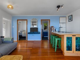 A living room with a sofa and kitchen counter at Ahipara in Kaitaia