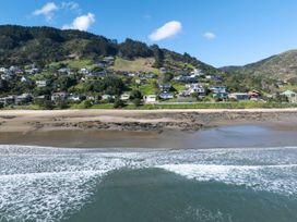 A beach with houses and mountains in the background at Ahipara in Kaitaia