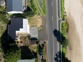 An aerial view of a house near a road and beach at Ahipara in Kaitaia