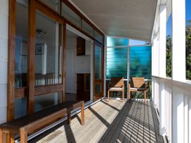 A porch with a wooden bench and chairs at Ahipara in Kaitaia
