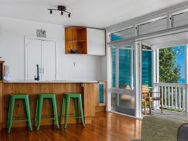 A kitchen with bar stools and glass doors at Ahipara in Kaitaia