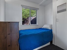 A bedroom with a bed and dresser at Ahipara in Kaitaia