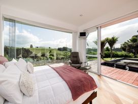 A bedroom with a bed and recliner chair at Solar House - Kerikeri Holiday House in Kerikeri