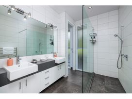 A bathroom with dual sinks and a glass shower at Solar House - Kerikeri Holiday House Kerikeri