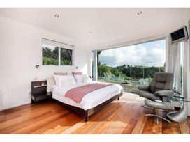 A bedroom with a bed and a chair at Solar House - Kerikeri Holiday House Kerikeri