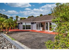 A house with a patio and palm trees at Solar House - Kerikeri Holiday House in Kerikeri