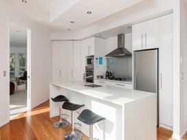 A kitchen with a central island and bar stools at Solar House - Kerikeri Holiday House in Kerikeri