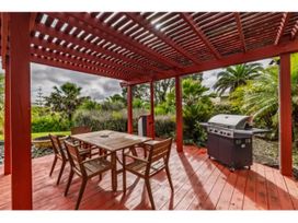 A patio with a table and chairs alongside a grill at Solar House - Kerikeri Holiday House in Kerikeri
