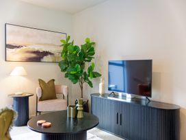 A living room with furniture including a television and a plant at Ocean Whisper Retreat - Kaikoura Holiday Home