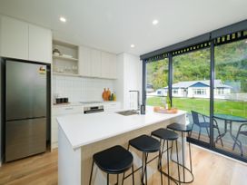 A kitchen with bar stools and modern appliances at Ocean Whisper Retreat - Kaikoura Holiday Home