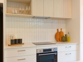 A kitchen with cabinets, cooktop, glasses, and cutting board at Ocean Whisper Retreat - Kaikoura