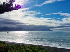 A beach with the ocean and mountains at Ocean Whisper Retreat - Kaikoura Holiday Home