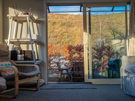 A living room with a view of a patio and mountains at Arrowtown Gold - Elevated Luxury Apartment in Arrowtown