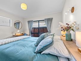 A bedroom with a bed and a table at Papamoa Waves - Seaside Getaway, Papamoa