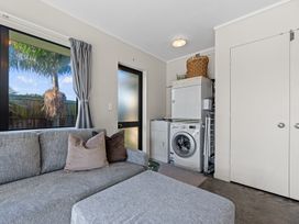 A laundry room with a sofa and appliances at Papamoa Waves - Seaside Getaway, Papamoa