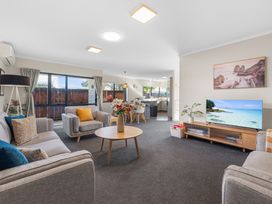 A living room with a sofa and television at Papamoa Waves - Seaside Getaway, Papamoa