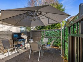 An outdoor seating area with a grill and table at Papamoa Waves - Seaside Getaway in Papamoa