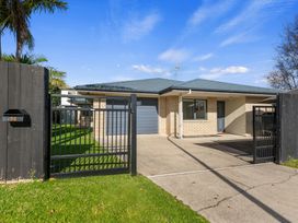 An outdoor view of a house with a gate and driveway at Papamoa Waves - Seaside Getaway in Papamoa
