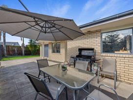An outdoor patio with a table and chairs at Papamoa Waves - Seaside Getaway in Papamoa