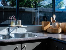 A kitchen with a sink and wooden utensils at Papamoa Waves - Seaside Getaway in Papamoa