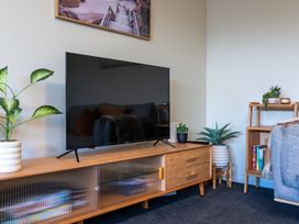 A living room with a television and a bookshelf at Papamoa Waves - Seaside Getaway, Papamoa