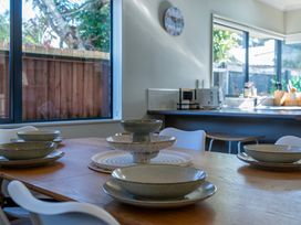 A dining room with plates on the table at Papamoa Waves - Seaside Getaway, Papamoa