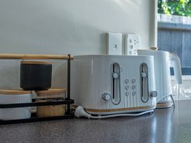 A kitchen countertop with a toaster and kettle at Papamoa Waves - Seaside Getaway, Papamoa