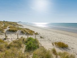A beach with sand dunes and water at Papamoa Waves - Seaside Getaway, Papamoa