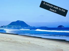 A beach view with waves and a mountain at Papamoa Waves - Seaside Getaway in Papamoa