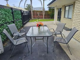 An outdoor seating area with a table and chairs at Papamoa Waves - Seaside Getaway in Papamoa