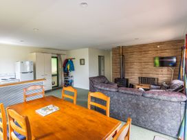 A living room with a dining table and refrigerator at Alpine Charm - Ohakune Holiday Home, Ohakune