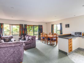 A living room with a sofa, dining table, and kitchen area at Alpine Charm - Ohakune Holiday Home in Ohakune