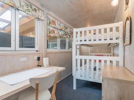 A bedroom with a bunk bed and desk at Home Away From Home In Whangamata