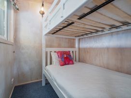 A bedroom with a bunk bed and a light fixture at Home Away From Home In Whangamata