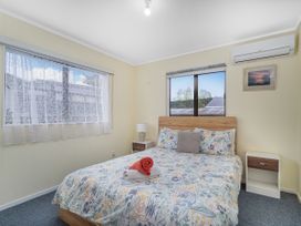 A bedroom with a bed and a lamp at Home Away From Home In Whangamata